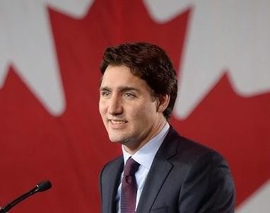 Justin Trudeau podczas wystąpienia publicznego, gestykulujący w kierunku widowni, symbolizujący jego zaangażowanie w politykę i kontakt z obywatelami.