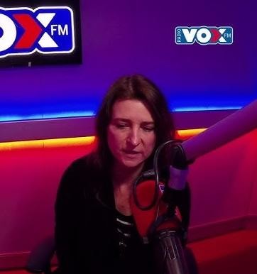 Renata Dąbkowska w trakcie występu na scenie, śpiewająca z pasją, z mikrofonem w dłoni, otoczona światłami.