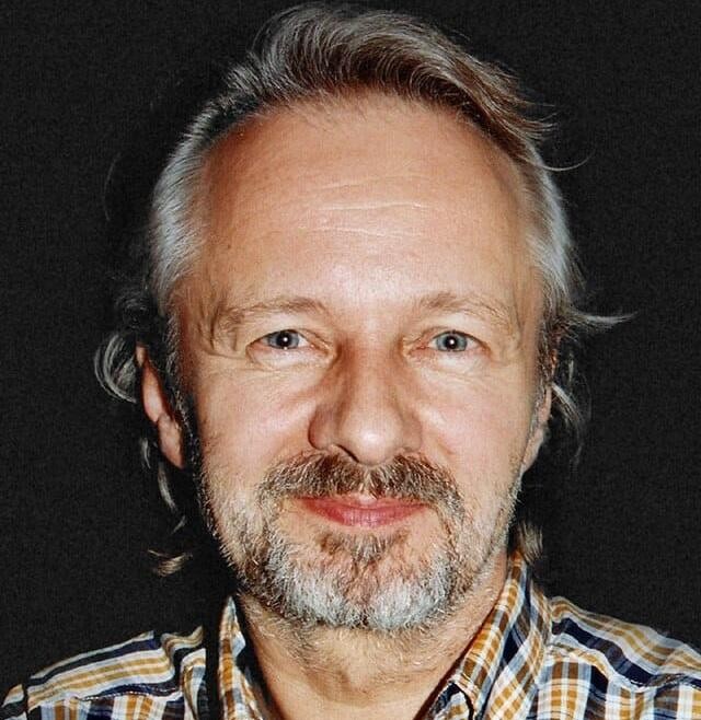 Krzysztof Stroiński w akcji, wcielający się w rolę filmową lub teatralną, z intensywnym wyrazem twarzy, przedstawiony w dynamicznym ujęciu, oddającym głębię jego aktorstwa.