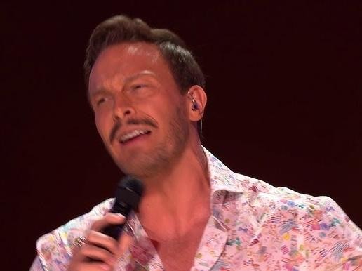 Sławek Uniatowski podczas występu na scenie, śpiewający lub grający na instrumencie klawiszowym.