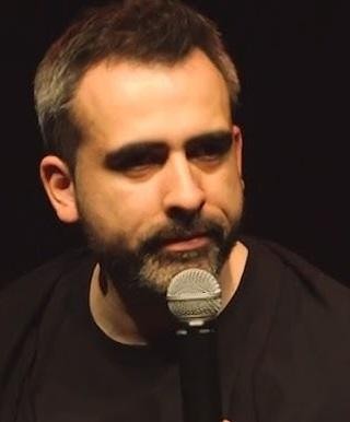 Abelard Giza na scenie podczas występu stand-upowego, z widoczną rozbawioną publicznością.