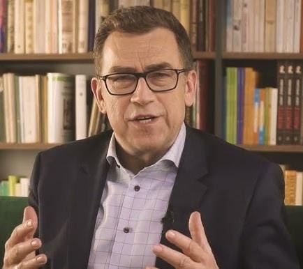Maciej Orłoś prowadzący szkolenie z wystąpień publicznych, gestykulujący do słuchaczy.
