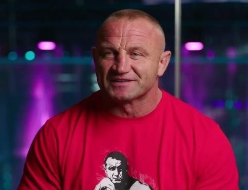 Mariusz Pudzianowski walczący w oktagonie MMA, z widoczną determinacją i siłą.