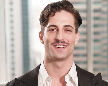Damiano David z Måneskin w trakcie energicznego występu na scenie, śpiewający do mikrofonu, z widocznymi instrumentami zespołu i efektami świetlnymi, w swoim charakterystycznym stylu.